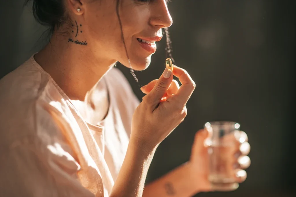 mulher tomando cápsulas de suplemento alimentar