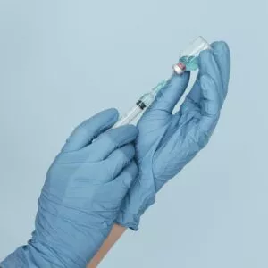 hands with gloves holding vaccine syringe