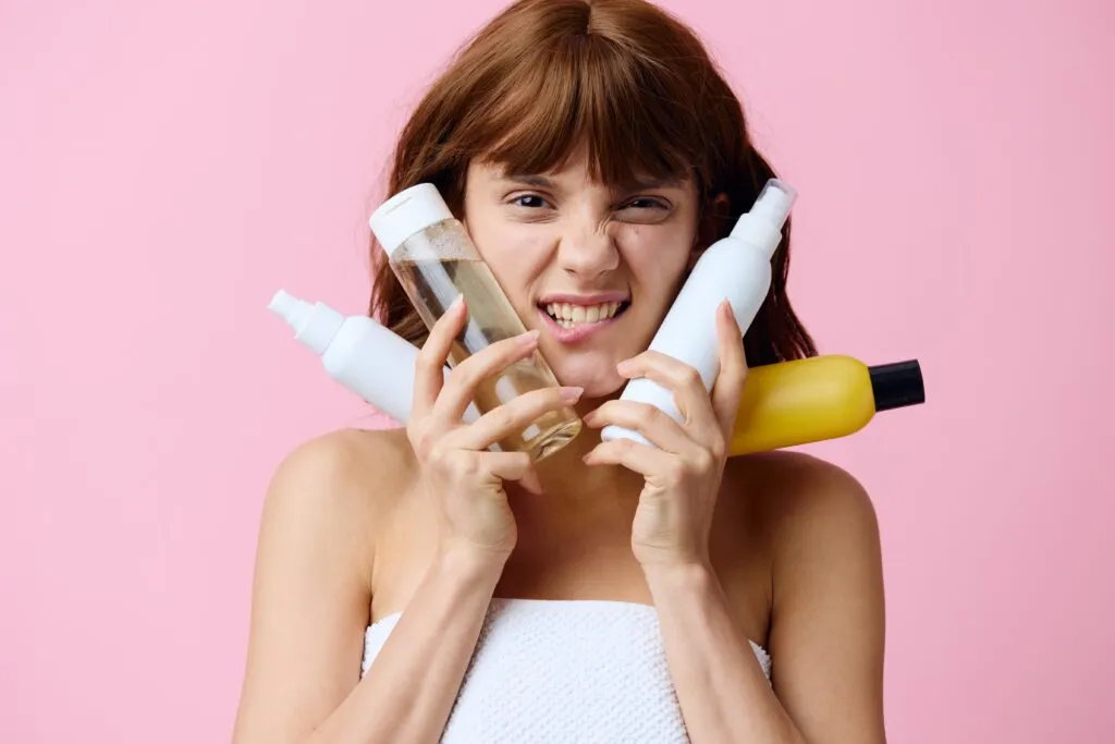 portrait young woman holding bottle against pink background