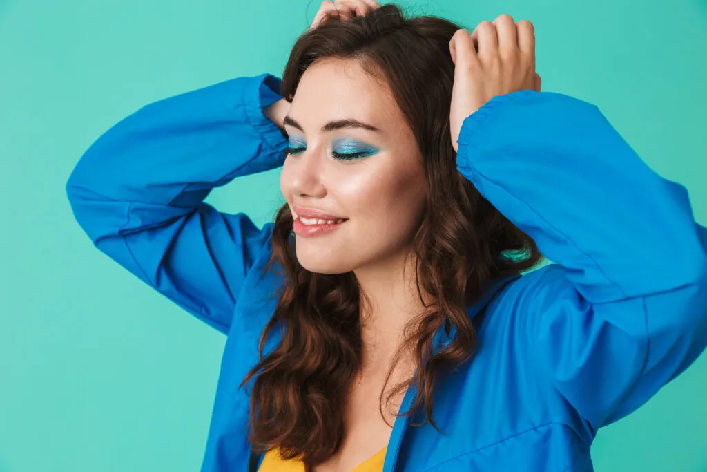 beautiful brunette woman wearing raincoat jacket holding hands head with closed eyes